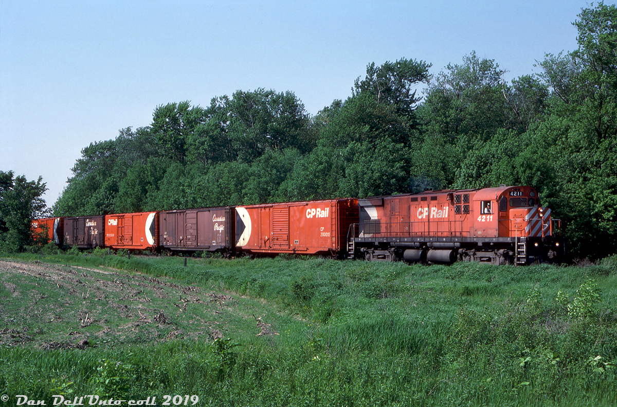 CP C424 4211 heads south on the Port Burwell Sub with a cut of 50' combo-door boxcars in tow for Tillsonburg, about to cross Daniel Street just to the south of Mount Elgin. As mentioned before, CP had modified its fleet of C424's for roadswitcher service in the early 80's and they were a common sight working the sleepy branchlines of Ontario solo or in pairs, as well as in mainline use with other units.

Originally part of the old Tillsonburg, Lake Erie and Pacific Railway built in the late 1890's and subsequently acquired by the CPR (as part of a 999 year lease), the Port Burwell Sub was another victim affected by the low-traffic branchline abandonments of the 80's, with the section to the south between Tillsonburg and Port Burwell having been abandoned the previous year in May 1987. The 17.6 mile stretch from Tillsonburg to Ingersoll remained active, and survived long enough for Ontario Southland to take over operations in 1999.


David P. Oroszi photo, Dan Dell'Unto collection slide.