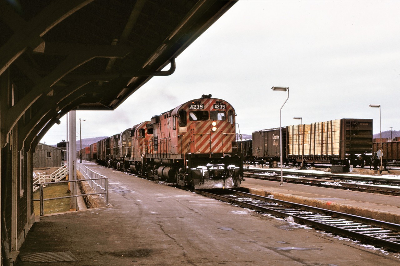 A derailment on the CP west of Sudbury, Ontario caused a number of trains to be diverted over CN.  An eastbound CP freight arrives at the CN station in Capreol, Ontario on November 10, 1973.  The train left CP rails at Franz, travelled to Oba on the ACR, and continued east on CN.  It will regain home rails again in Sudbury.  Power for the train is 3 C424s and a GP35: 4239 5020 4237 and 4235 in that order.