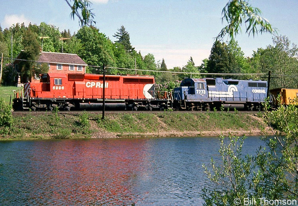 CP SD40-2 5996 leads leased Conrail GP38 7773 on a freight heading eastbound past the pond at Campbellville on a sunny day in May 1985.