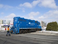 After dropping off ten grain cars at the P&H mill,  a crewmember flags the Bridge Street crossing as GMTX 2257 heads back light to the nearby Pointe St-Charles Yard.