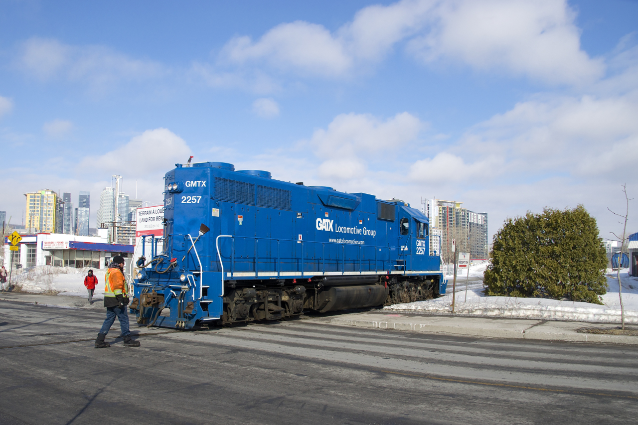 After dropping off ten grain cars at the P&H mill,  a crewmember flags the Bridge Street crossing as GMTX 2257 heads back light to the nearby Pointe St-Charles Yard.