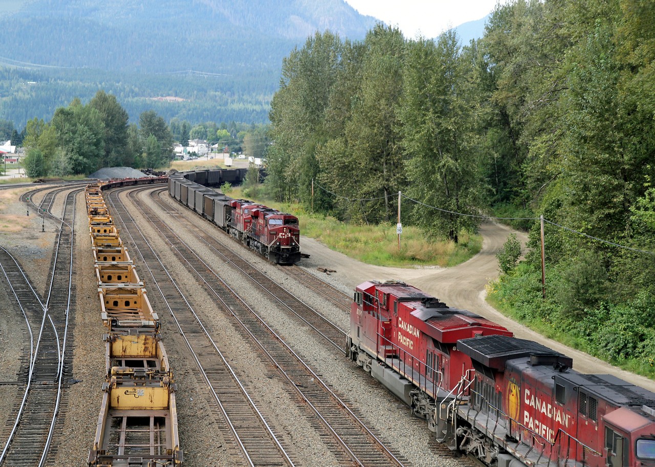 Sisters meet at Revelstoke.  CP 8892 east with empty coal gondolas meets CP 8891 west with loaded coal.  Notice AC4400CW CP 9723 just emerging from under the bridge seems to have had an argument with it's handrail somewhere along the way.