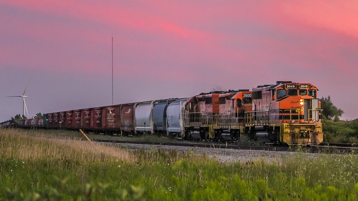 It was a Friday after work in the summer, and I was making my usual trek from Hamilton to Norfolk County (where I grew up and where I still spend a lot of my summer) for the weekend - I believe it was the chicken BBQ at the Teeterville Legion the following day. As usual, I stopped in to see what was up with the SOR on the way. I found them down in Nanticoke and it looked like they were getting ready to head in Garnet, so I waited around a bit for the "chase" north. They soon departed, taking their time between concessions, seemingly to allow me to catch them at every crossing where they would put on a good show each time. They arrived in Garnet as the sun was beginning to set, and tied the train down at the north end of the yard, so I waited around a bit to capture this shot. With word that 4001 (which had been sitting at Railcare since the CN takeover in Hamilton in December 2018) went down to Garnet today on 580, it again got me thinking about 3049, which has sat seemingly untouched at Railcare since September. I am wondering if the sun has set for good on it, or what its future holds. 

The head end hoppers and centrebeams are to be dropped at CGC on the way to Paris, and it looks like a pretty healthy string of coils out of Stelco were heading north as well. The usual assortment of tanks brought up the rear. The trailing units were QGRY 2500 and RLHH 3404.