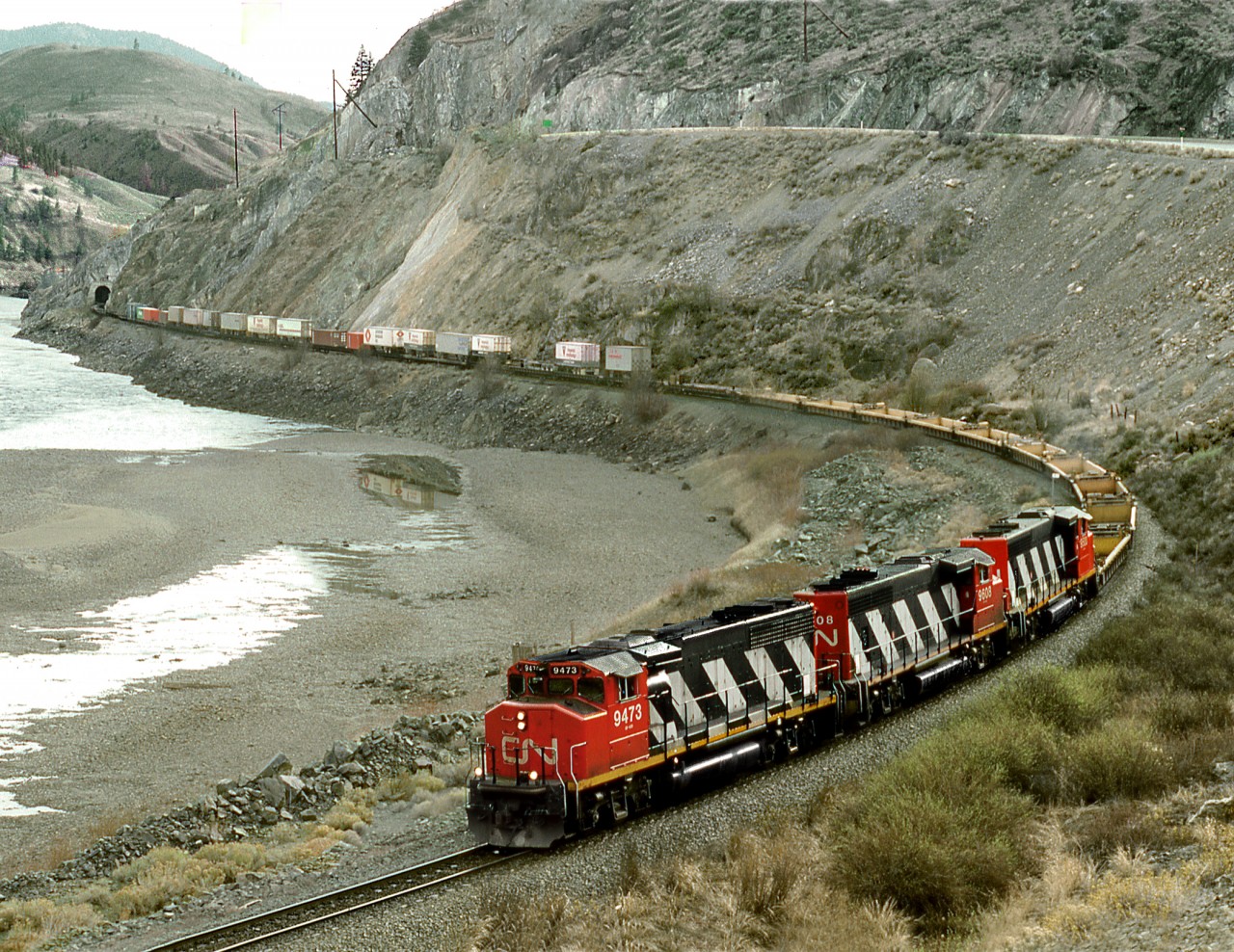 An eastbound clears the Martel tunnel along the Thompson River west of Kamloops. Only westbounds now traverse this track since directional running with CP. Eastbounds on CP on opposite side river and westbounds only on CN