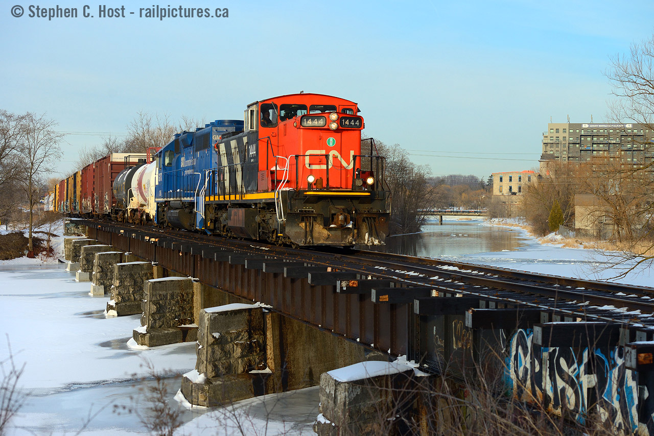 CN 542 with a rather large train passes over the Speed River in Hespeler. Built by the Great Western Railway (Galt and Guelph) it's likely that this bridge was built in 1857 (and possibly upgraded since then). In 2018 not long after the takeover from GEXR CN completely re-decked the entire structure in a move unseen in many many decades. The town ever changing, mills built by the town founder, Jacob Hespeler, are being converted into Condos in the background. That site, later known as an American Standard factory also had direct rail service via the former Grand River Railway's (CP) Hespeler Branch. The GRR/CP Hespeler branch crossed the CN at a diamond behind me and ran along the river to the left of this photo to the mill. In 1991 CN took over direct rail service to the plant when CP Abandoned a portion of the Hespeler branch and eliminated the diamond and signals that protected it. Remnants of the rail line lingered into the early 2000's as crossbucks were still located at the American Standard site on Guelph St despite rails being pulled some years earlier. I'll post some GEXR photos of this bridge later - it was quite scary to watch GEXR Trains cross this structure.Note: Some data sourced from George Roth's book "Steel Wheels along the grand" - copies were once upon a time sold at Credit Valley Railway for those interested in this area. The maps and photos and history are very very much worth the price of admission.