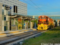 GEXR makes a daylight appearance at the newly constructed University of Waterloo ION LRT station. 2073 reflects in the architecture  as the train traverses a sight likely unique for Canada: A functional Gauntlet Track - automatic switches on either end of the platform switch the train to the Gauntlet (outer track) to avoid the close clearance of the platform. <br><br>This was NOT easy to do. I figured perhaps on the longest days of the year it may be possible to get 584 in Daylight up to Elmira. I tried for 4 years after last shooting this in 2014 and the lease was coming due so this was my last summer to try it. So here we are exactly on the 2018 summer solstice, 8:30 PM at the University of Waterloo's LRT station, and there's still just enough light to eek out this shot which I found by un-happy accident a couple weeks prior. Un-happy because I got my daylight shots on June 7th and I thought I nailed it - after one of my shots <a href=http://www.railpictures.ca/?attachment_id=35028 target=_blank> a block south of here</a> I chased a bit, saw this shot, and realized, dammit, I have to go back and get this - it just looked too good to pass up. I had to try again. I got lucky. ION Service is expected to begin very soon as they target a real Spring 2019 start-up.<br><br>Shameless plug time: In the March 2019 <a href=http://www.railpace.com/subscribe/ target=_blank>Railpace Magazine</a> now  at select newstands and hobby shops, the cover issue is a retrospective on the Goderich-Exeter Railway by Jason Noe, and I had the pleasure to submit a number of my photos to this photo-packed issue. There's a number of never before seen photos by me in there, along with lots of Jason's fine work and a great 10/10 photo by Jason Bartlett. I promise plenty of surprises to those who buy a copy <a href=http://www.railpace.com/subscribe/ target=_blank>or subscribe</a>. Railpace is neat as you get a hundred and change photos each issue (It's really just a photo gallery magazine!) along with a great summary of news across the US and Canadian east.  We appreciate your support of the printed word for those that do go get a copy! (Please add a comment below if you know where to pick up a copy!) Cheers.