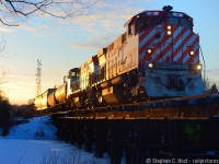 Blue hues of a quickly darkening sky reflect off the frozen Eramosa River as oranges of a winter sunset predict a Sailor's delight on the morrow. You'd be hard pressed to miss this train at night: 10 lit up objects adorn the lead locomotive: Number Boards, class lights displaying "extra", two headlights, and four ditchlights, the extra set added to see around curves in the mountainous territory of British Columbia. This was winter's last stand in 2019 - a rare frigidly cold March day just as daylight savings was about to creep in - so too would the warmth and with it goes all the snow.
<br><br>
I did a similar photo in early 2004 with my first junk digital camera, it was a pleasure to have the chance to try this again, I have had this on my mind for quite some time to try but just never made it happen.
