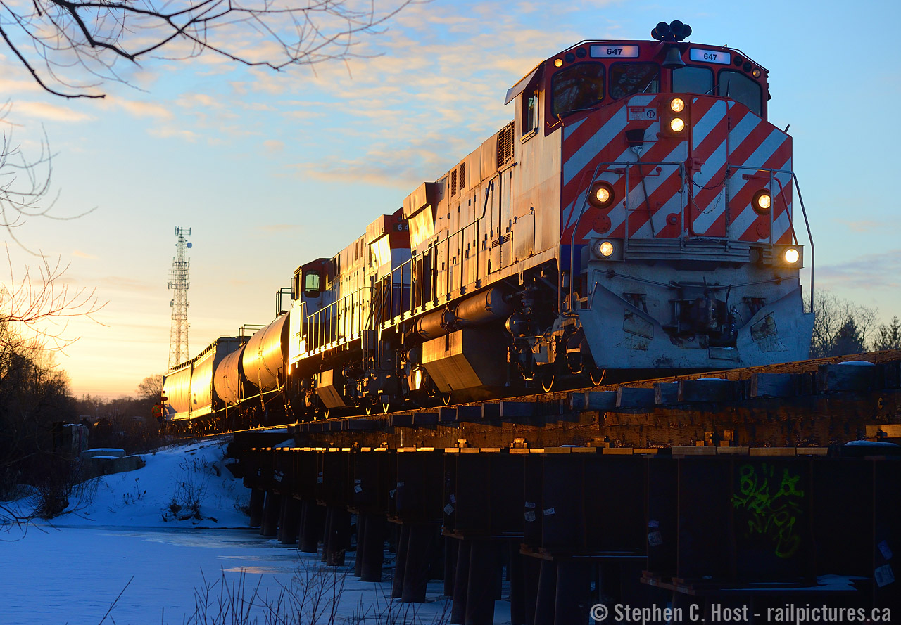 Blue hues of a quickly darkening sky reflect off the frozen Eramosa River as oranges of a winter sunset predict a Sailor's delight on the morrow. You'd be hard pressed to miss this train at night: 10 lit up objects adorn the lead locomotive: Number Boards, class lights displaying "extra", two headlights, and four ditchlights, the extra set added to see around curves in the mountainous territory of British Columbia. This was winter's last stand in 2019 - a rare frigidly cold March day just as daylight savings was about to creep in - so too would the warmth and with it goes all the snow.

I did a similar photo in early 2004 with my first junk digital camera, it was a pleasure to have the chance to try this again, I have had this on my mind for quite some time to try but just never made it happen.