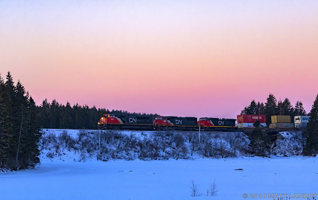 At sunrise, CN Q120 begins it's climb towards Evans, seen here passing Palmers Pond at Dorchester, New Brunswick.