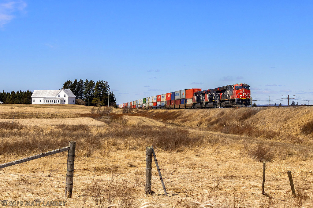 After heading along the Tantramar Marsh, stack train Q120 is about to cross the New Brunswick/Nova Scotia border, approaching Fort Lawrence, NS on a beauty of a day.