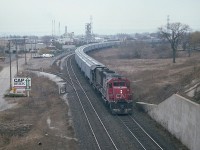 Here's an angle not often utilized. I'm standing on the old Hwy 2 bridge (later Plains Rd East) looking South. If the sun was out, this shot would not be possible. A unit train of some sort with a pair of SD-40s up front. In the background, left, one can see the Fariview Av bridge, and just to right centre behind the train is the Burlington West station, barely visible. And behind that, the chemical operations and the yard that once was a busy place. The train is just coming off the Oakville onto the Halton, Toronto-bound.