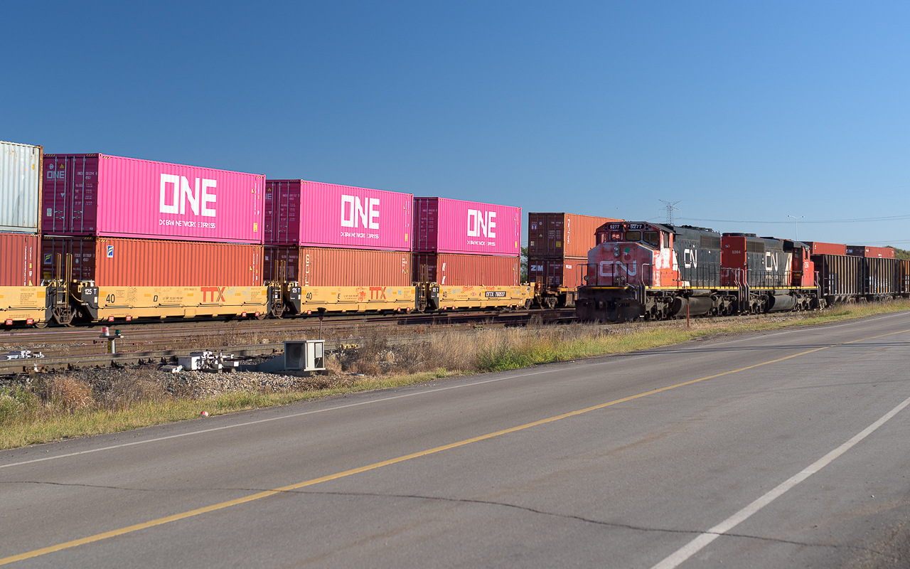 When stopping in at Clover Bar on this morning, I happened to find CN 5277 and 5264 sitting on the lead from the Wainwright Sub. to Clover Bar yard with a train of loaded hoppers. As I walked to a spot to take a photo, I noticed these containers coming on the passing train. Quickly getting myself re-positioned, I caught this odd picture. The SD's must feel that they are close to "seeing it all" with PINK containers going by.