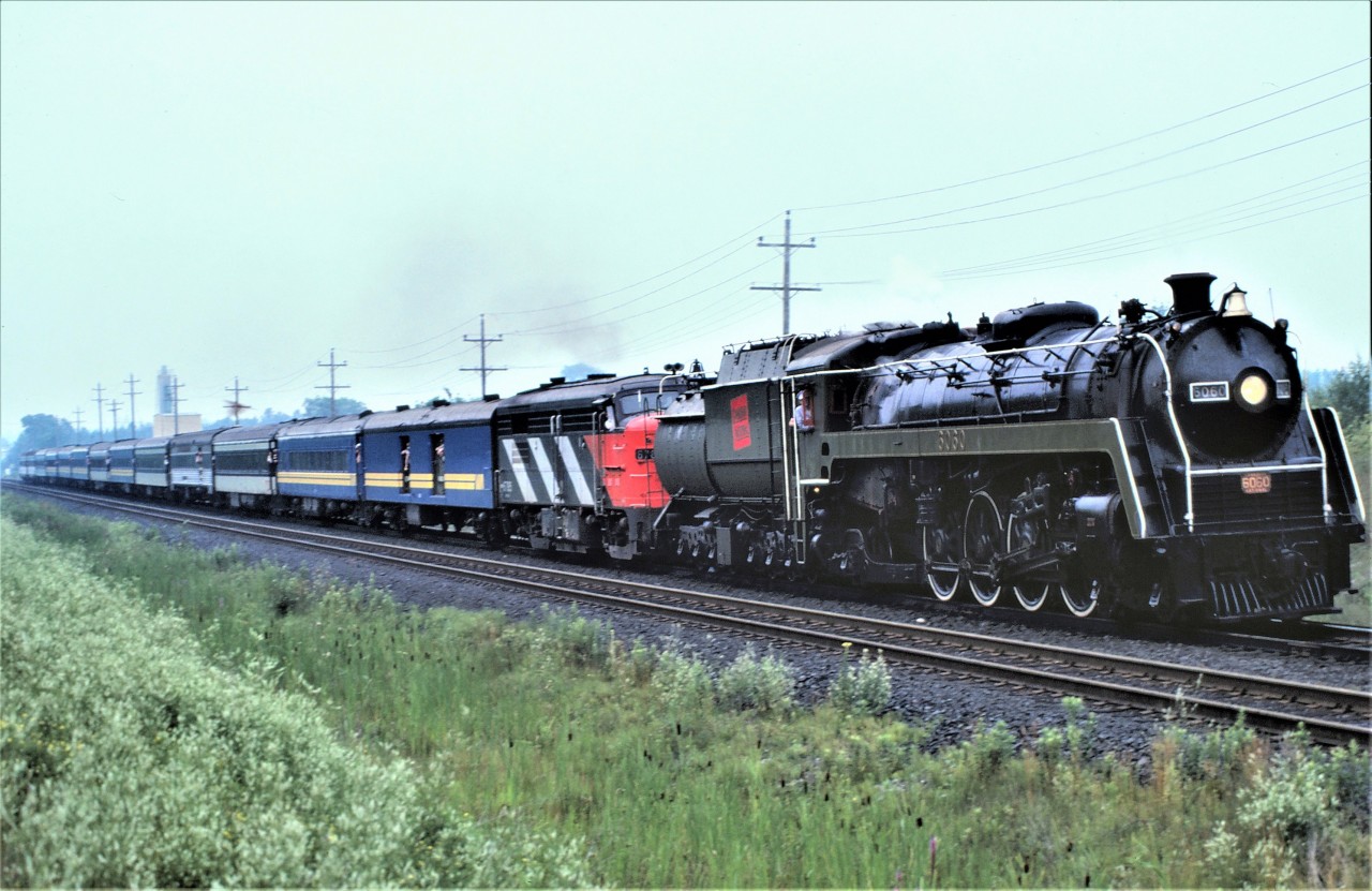 On a very smoggy Saturday morning, July 26, 1980, CN ran a circle excursion to Washago ON with CN's 4-8-2 6060.  The train ran north on the Bala Subdivision and south on the Newmarket Subdivision.  The 13 car train was assisted by FPA-4 6785.  The photograph was taken just south of the Richmond Hill station.  It is interesting to see more than 20 "heads" hanging out of the cars.

Can someone please identify the 4th car on the train.