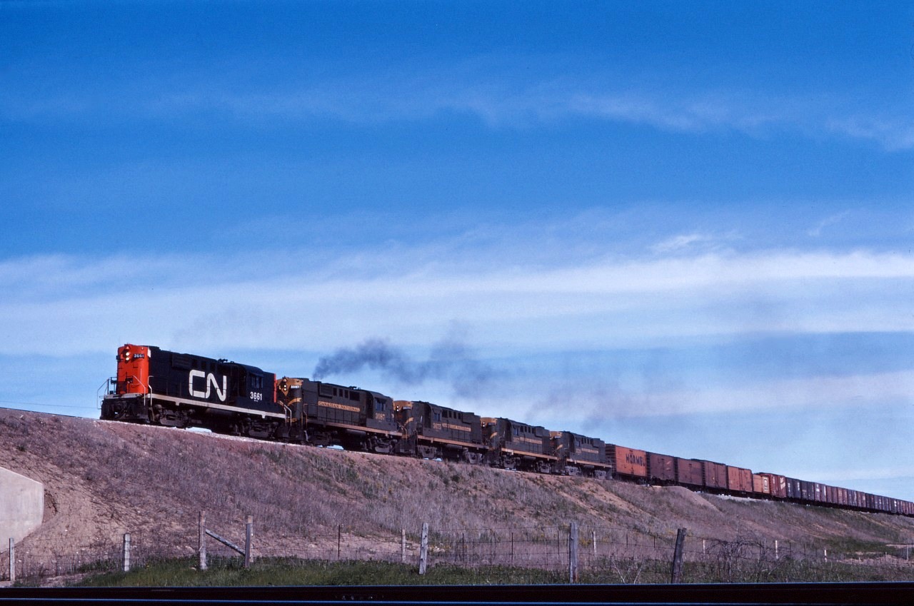 Four RS18s and an RS10 (3661, 3087, 3675,3657, and 3726) lead a westbound up and over the CP Galt sub in Milton on a fine June 1965 day. Note those ice-cooled refrigerator cars up front, returning to the United States!