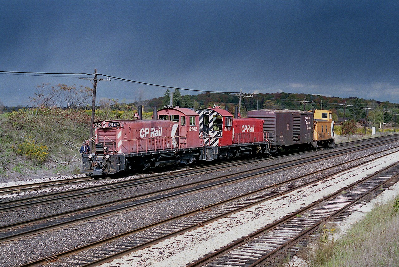 I used to think it was rare enough when I got some sunshine, and as you can see I wasn't going to have it for long.  Bit of a cloudburst off in the distance adds flare of dramatics to this image of a westbound local coming in to Guelph Jct ., with CP 8142 and 8155 with a very short train. I miss those diminutive SW 1200s; they are all gone from CP roster now; 8142 left for the states in 1999 and 8155 retired, 2008.
At the time this image was shot in late 1988 the CP station still stood, a bit out of the photo to my left.