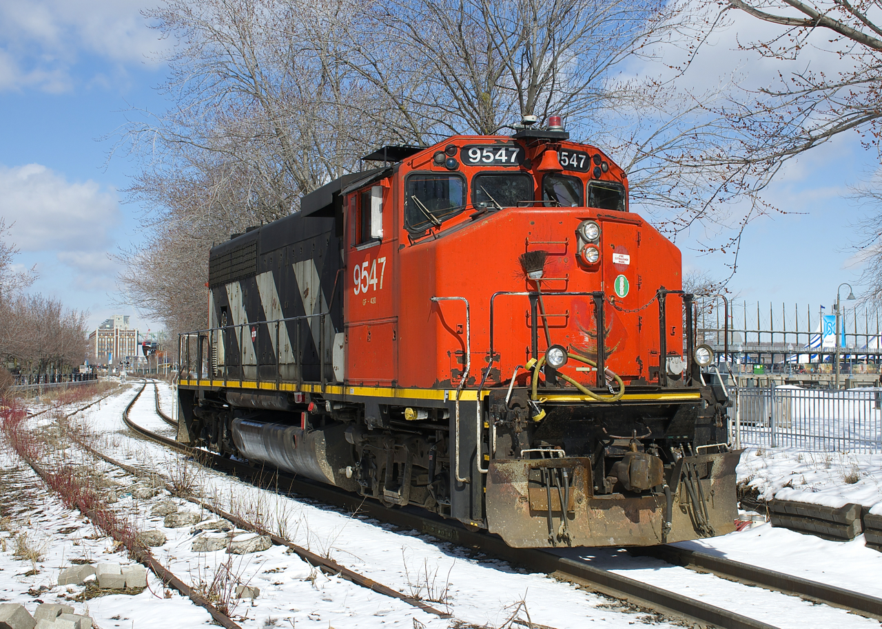 After bringing in cars to the Port of Montreal, CN 9547 is leaving light power as it passes an out of use siding at left.