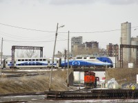 As the first departure of the afternoon for Mont Saint-Hilaire (EXO 810) flies by overhead on the CN St-Hyacinthe Sub, CN 9547 awaits its next assignment in the Pointe St-Charles Yard.
