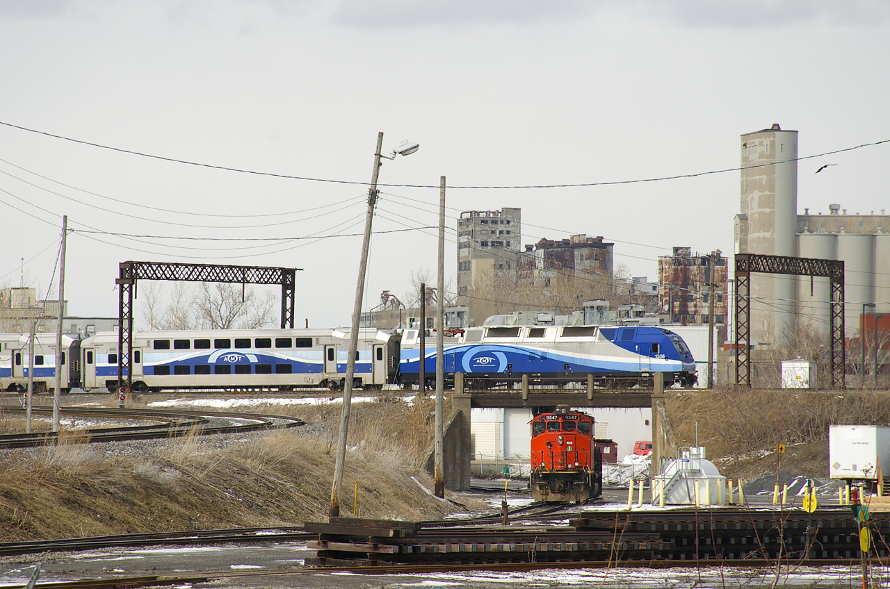 As the first departure of the afternoon for Mont Saint-Hilaire (EXO 810) flies by overhead on the CN St-Hyacinthe Sub, CN 9547 awaits its next assignment in the Pointe St-Charles Yard.