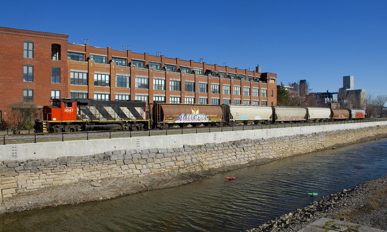 CN 9547 shoves 6 loaded grain car towards the Ardent mill, the last client remaining on the East Side Canal Bank Spur. It is passing what was once a Stelco plant, but is now condos.