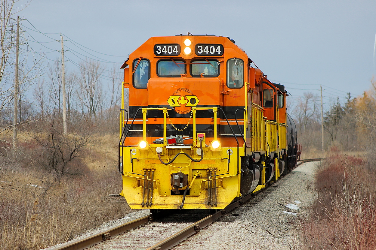 RLHH 3404, RLHH 2111, and RLHH 3049 are the power for the day's 595. After building their train in Garnet and heading south for Nanticok, they set off the refinery traffic north of Concession 4 and are pictured here just outside of Stelco with two tanks and one coil car to set off. They would wye the power within the Stelco property and 3404 would lead back out.