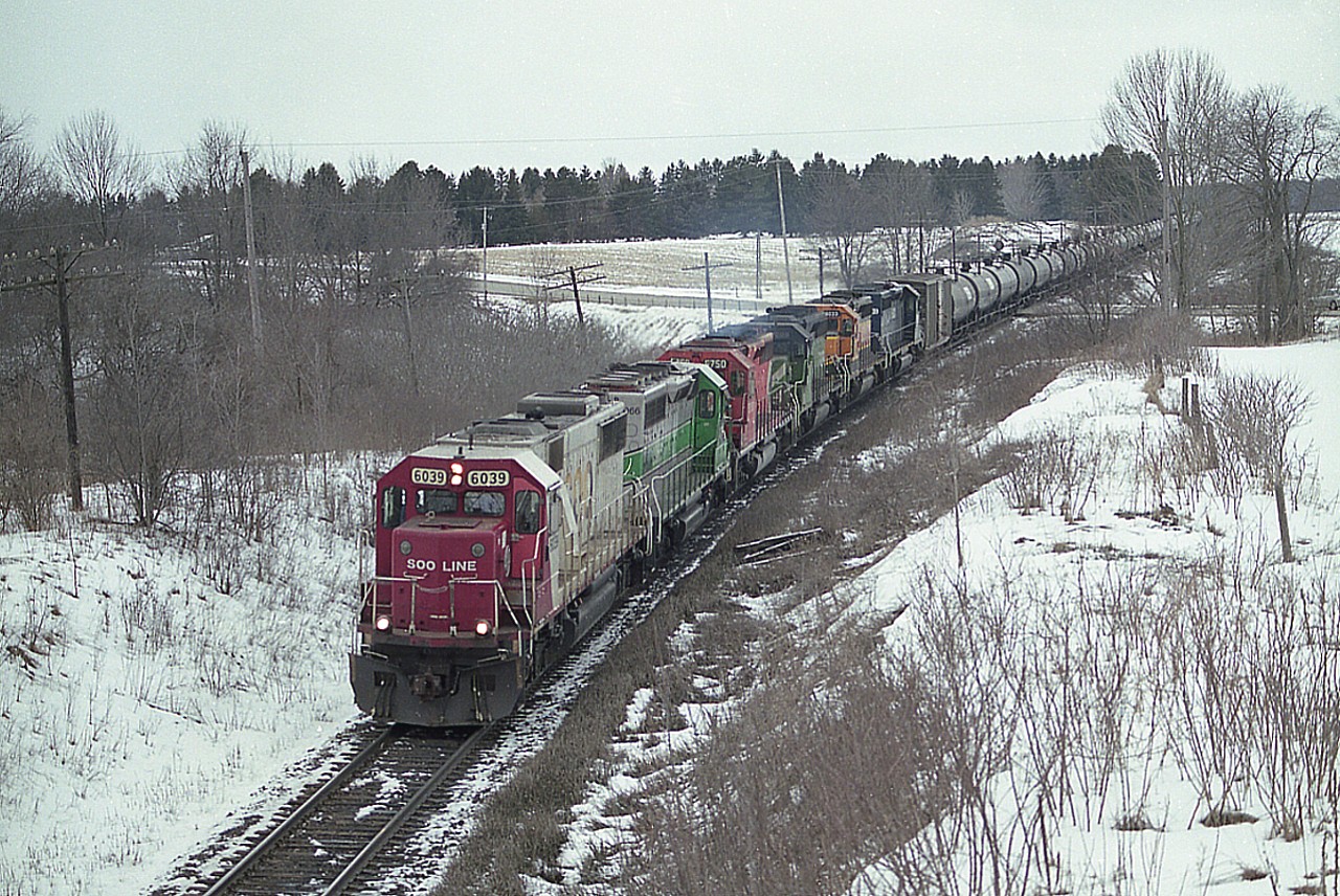 There were fun times to be had for the trackside gang in 2010/2011 when it came to catching the rather plentiful ethanol trains on CP. Most often they sported 4 units; CP and CSX were common; but for me the height of it was this rather wild 6 unit lashup seen here crossing Hwy 2 west of Woodstock. It was a mad dash to get to this spot, a farm bridge over the tracks. This train was really moving.  SOO 6039, CITX 3066, CP 5750, HLCX 7009, 8033 and 7193 was, for colour, about as good as it got. Pity it was another ugly cloudy grey day.