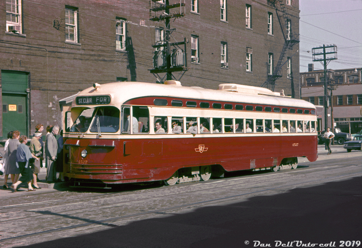 A warm June day in 1961 finds TTC A8 PCC 4527 taking on a load of passengers at the southeast corner of Bathurst and King Streets, working the "Fort" route north to St. Clair. The Fort car was a branch that operated along Bathurst between Fleet Loop (on Fleet St. west of Bathurst), up Bathurst to Woseley Loop at Queen St., or up to St. Clair Avenue as this car is signed.

The A8-class of all-electric PCC streetcars were a group of 50 numbered 4500-4549. They were Toronto's "newest" PCC's, being built by CC&F in 1951, and also the final order purchased new by the TTC (various groups of used cars would be purchased in the following years). 

While Toronto's once-mighty PCC fleet was being phased out in the 80's with the delivery of the new CLRV & ALRVs, a select group of 19 A8's would be rebuilt into 4600-series A15 cars for operation on the new Harbourfront LRT that opened in the early 90's, and most of those rebuilt cars survive today at various museums and tourist operations, including two retained by the TTC for special events.

John F. Bromley photo, Dan Dell'Unto collection (this was an old Ektachrome slide that had basically fully cyan-shifted, a good amount of digital TLC and tweaking was needed to help bring the colours back).