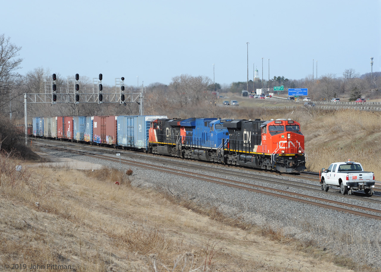 Eastbound CN train 422 originating in Port Robinson is passing through CN Snake where it crosses over to Track 1, with high-cube boxcar loads of auto parts for Ford in Oakville at the front end. 
Three different GE locomotives power the train - ES44ac, ET44ac, and ES44dc.  
The foreman's pickup truck heading west on Track 2 surprised me, meeting 422 here.
This viewpoint is more enjoyable while the ticks are dormant.