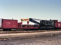 This 1927-built Industrial Works steam crane of 150 Ton capacity was parked on a CN siding in London, in pictures taken in 1991 and 1992. It is Conrail's CR 50125, ex- PC 50125, probably based in St Thomas before being retired from Conrail's southern Ontario operation.<br> From left to right are CN 10650 Express Refrigerator built 1957 with ice hatches ("No Brakes" stencil), CN 60200 "The Pas Auxilliary Tie & Block Car", CR 50125 crane, and CN 56483 which is a wood sheathed flanger missing some boards. <br> All retired and awaiting scrapping - which might have been delayed because of asbestos insulation. <br> <i>Caption rewritten based on information from the comments, thank you.</i>