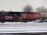 "There were 6 Stelco engines disposed of during Jan/Feb 1995. They all shipped CN to Windsor and then CSX to McDonald Ohio for buyer Larry’s Truck Electric.<br>
SW-8 71, 74, and 76; SW900 78, 79; and G.E. 80ton 54.<br>
The G.E. plus 74 and 79 were all in pieces, in gondolas, the others were able to move on their wheels." <br><br>
Quote above from Mr. Mercer's comment on my previous Stelco submission. <br>
In this image, the front of the cab of scrapped GE 80ton Stelco 54 is visible above the gondola side.  The red bell that appears to be above it is part of the CN locomotive on the next track. <br> 
GMD SW8 Stelco 76 carries an air-brake jumper hose connecting the railcars on either end of it.<br>
Location mapped is approximate.  	