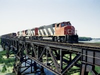 Nice afternoon as a trio of GP40-2L widecabs, led by CN 9511, rolls over the big trestle spanning the Jordan Harbour en route to Fort Erie from Mac Yd. Note the load of logs for the paper mill at Thorold South. This daily train, known as #469 back then, regularly had quite a few cars of wood for an extremely busy plant; which today, sits dead and empty.  Times change.