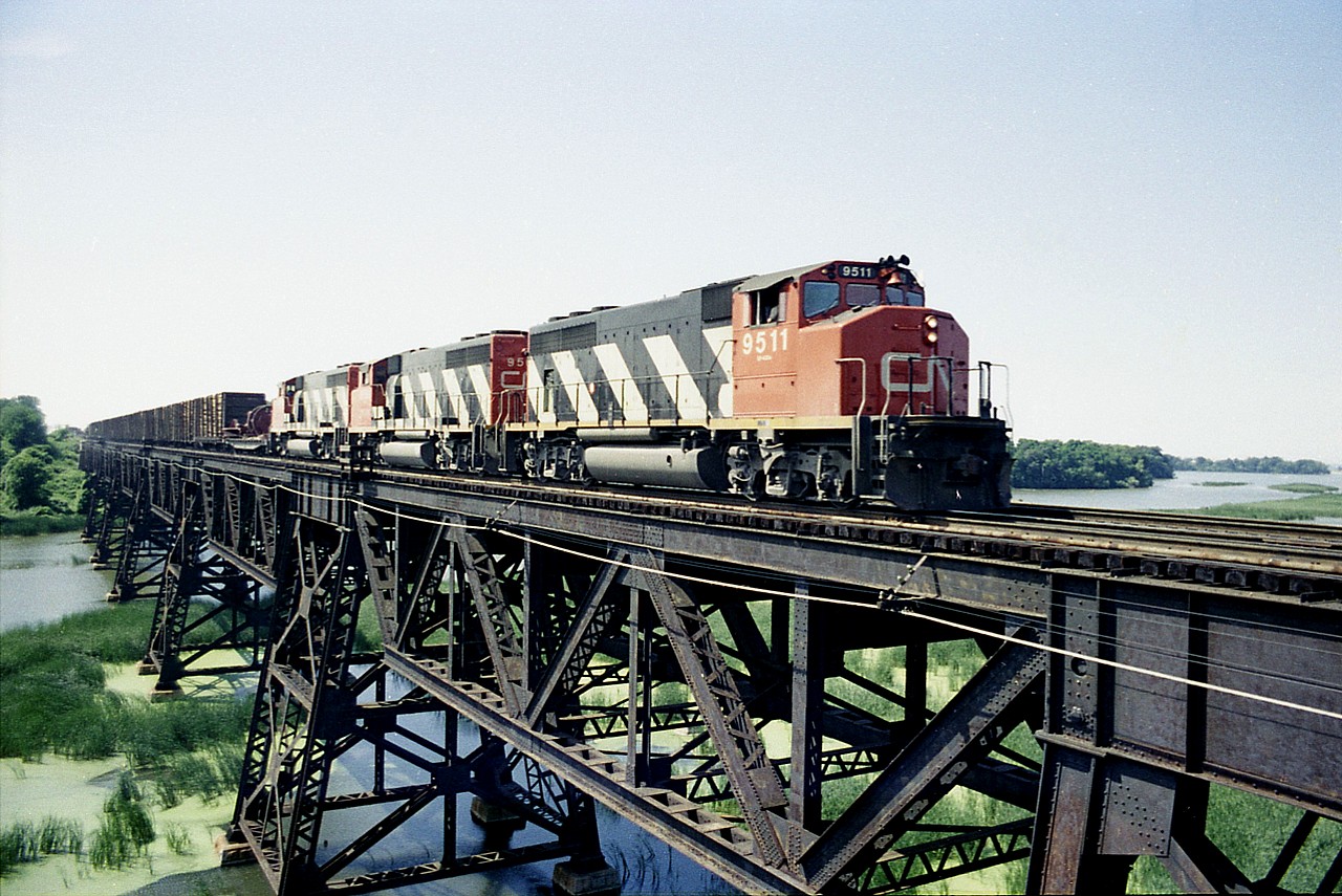 Nice afternoon as a trio of GP40-2L widecabs, led by CN 9511, rolls over the big trestle spanning the Jordan Harbour en route to Fort Erie from Mac Yd. Note the load of logs for the paper mill at Thorold South. This daily train, known as #469 back then, regularly had quite a few cars of wood for an extremely busy plant; which today, sits dead and empty.  Times change.