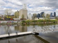 CN 9547 shoves three loaded grain cars to the Ardent mill. In the foreground is the Lachine Canal and in the background is downtown Montreal.
