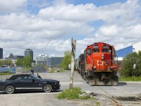 A Mustang waits for GP9's CN 7075 & CN 7229 to clear Bridge Street as they shove three loaded grain cars towards the P&H mill.