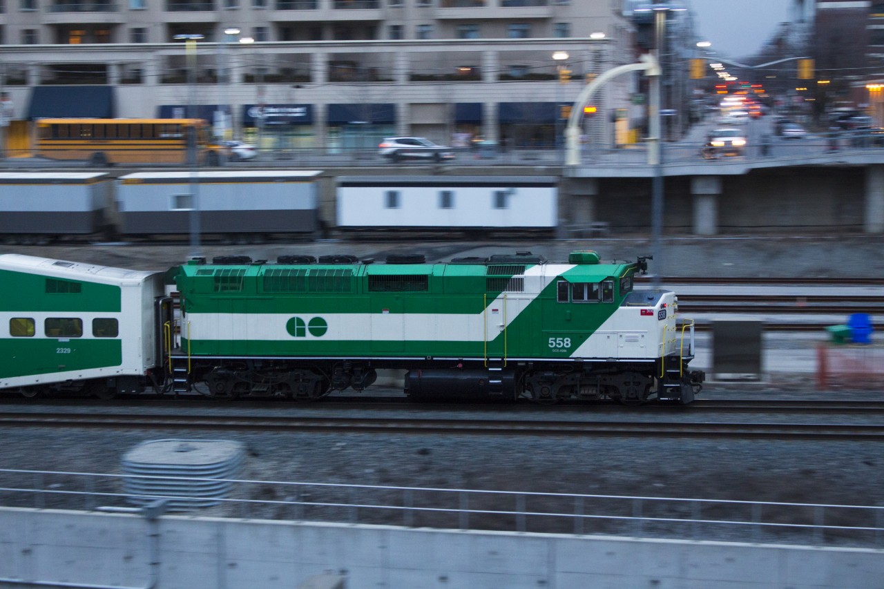 A GO Transit F59PH shoves an outbound commuter train out of Toronto at dusk.