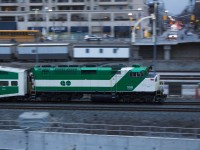 A GO Transit F59PH shoves an outbound commuter train out of Toronto at dusk. 