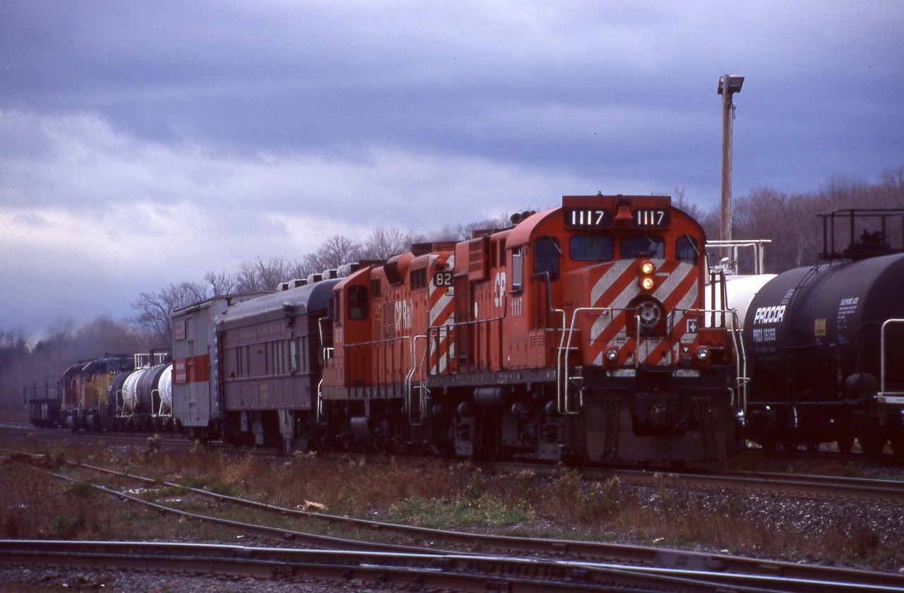 This photo seemed fitting for this dreary weather. It’s hard to believe I shot this over 20 years ago, but this day after work I made it up to Guelph Jct. and managed to catch the rail geometry train stopping on the main so the crew could take a break in the office. Back then the 1117 was still with its original mother, GP9 8243 but within a few years it would find a new mate GP38 3057, which it would be mated to until its last days before being scrapped in 2003. Behind the train a westbound with a former Union Pacific SD40 trailing can be seen just about to head out onto the OCS.