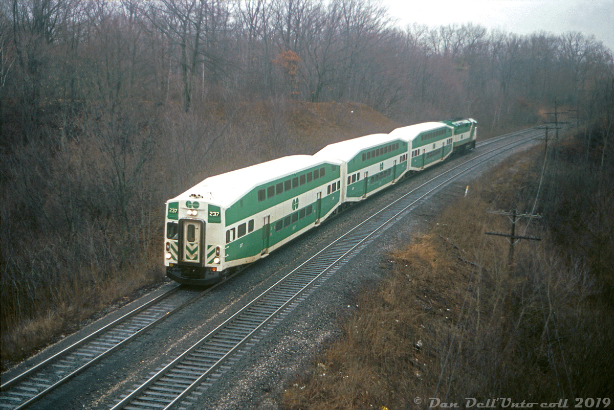 It's not a GO train, but it is GO equipment: VIA train #71 is operating a short GO Transit consist of three bilevels and an F59PH (an "L3"), seen rounding the curve on this gloomy day on the approach to Bayview Junction before heading up the Dundas Sub. GO Transit cab car 237 leads the charge, with F59PH 544 pushing on the rear end. If operating on time this would be VIA #71's usual ~9am appearance at Bayview, according to the timetable.

This was one of at least four sets of GO Transit equipment pressed into VIA service at the time, as defective axles failing on VIA LRC cars in February and March 1992 caused VIA to pull its entire fleet of LRC cars out of service effective March 17th due to safety concerns. In turn, VIA had to scrounge about for any replacement equipment it could find: old blue & yellow VIA cars coupled to steam generators pulled by F40's, LRC locomotives and old FP9's, Budd equipment that would normally be found on The Canadian, and borrowed equipment from GO Transit including bilevels, GP40's, APCU's and F59's were all pressed into VIA service until new replacement axles were made and installed in the entire LRC car fleet. No doubt there was a slight lack of comfort in having to ride a GO bilevel commuter coach on the 4+ hour trip for anyone travelling all the way from Toronto to Windsor.

Reg Button photo, Dan Dell'Unto collection.

For more info about the VIA LRC wheel failures and equipment substitutions, have a look at the May 1992 issue of Branchline here