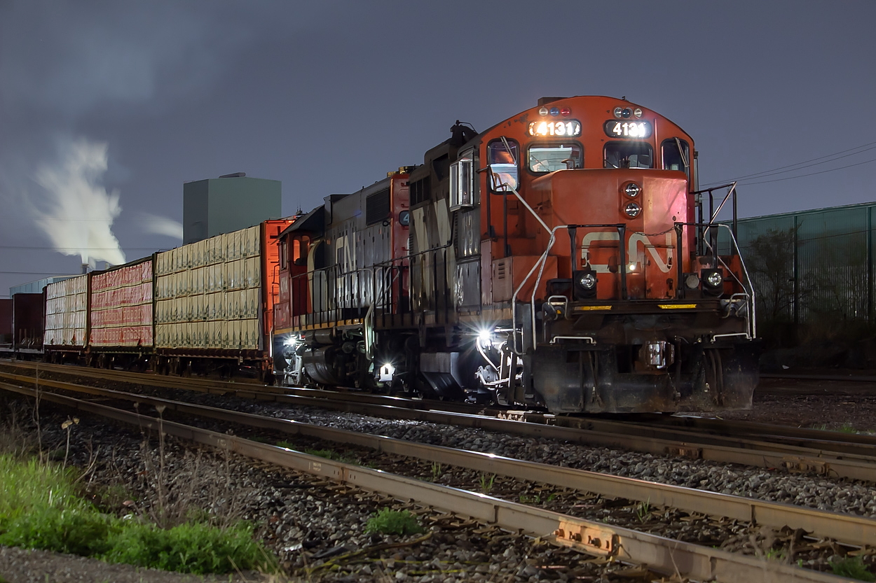 I have been having a lot of fun recently experimenting with night shots. It is fun to try something new. Here, 555 is pictured setting off the usual big string of gons, coils, and bulkheads at Parkdale Yard. The three loaded centrebeams on the head end are for Turkstra Lumber on Green Road. After the set off, they would proceed on the north track past Millen, and shove back onto the south track and into Turkstra.  It would appear that 555 is based out of Hamilton now - no longer calling Aldershot its home. 555 is a night job, and is using one of the yard sets at Stuart while the 2300 yard job uses the other. When 555 was transitioned to Hamilton at the beginning of May, they originally had a three pack of GP9s - 4131, 7022, and 7038. The other power set in the yard at the time was 1444 and 4704. On Saturday, 1444 encountered some issues and has since been sent back to Mac, leaving the two sets to be 4131 and 4704, and 7022 and 7038. The remote units on each are 4704 and 7022. Time will tell if they bring a third unit for the one set, as 555 has traditionally been a three unit job.