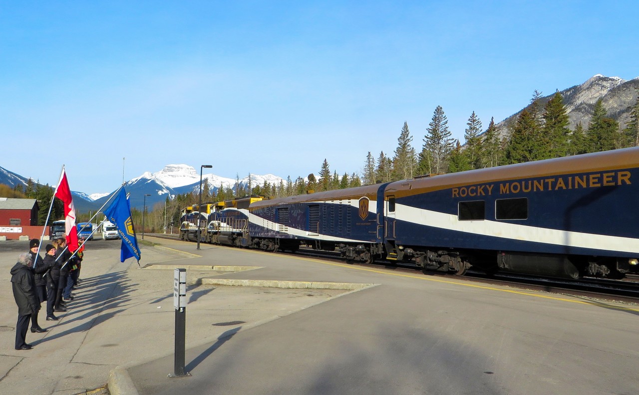 ROCKY MOUNTAINEER MOMENT. While visiting our son in Calgary, we took a side trip to overnight in Banff and were delighted to discover that the westbound Rocky Mountaineer would be stopping early the next morning to entrain passengers for Vancouver. An early morning rise allowed me to capture this 7:30 AM scene of GMD Unit GP40-2LW 8012 and sister 8014 at Banff with the 'First Passage to the West' Rocky Mountaineer. On the left side, the staff are proudly raising the flags of Canada, The Rocky Mountaineer Railtours Company, and Alberta to bid adieu to those who just boarded the all daylight train with an overnight stop in Kamloops. Almost 31 years earlier, on September 24, 1988 this photographer would re-board the westbound VIA 'Canadian' at this very spot and within hours, his girlfriend would accept his proposal of marriage.