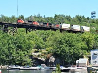 CN train 101 with 8024, 2318 and 8912 are northbound on the DRZ (Directional Running Zone) as they roll under historic Tower Hill and onto the 1695-foot Canadian Pacific trestle over the Seguin River and the busy Parry Sound harbour. 