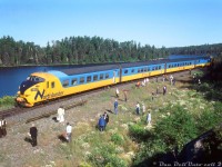 In August 1978, the Upper Canada Railway Society operated a four-day fantrip using one of Ontario Northland's recently acquired Northlander TEE trainsets. According to an old UCRS newsletter, the trip departed Toronto on Friday August the 4th and ran to North Bay. On the 5th it proceeded from North Bay to Timmins, on the 6th Timmins to Mosonee & back, and on Monday the 7th the train returned from Timmins back to Toronto. Here on the morning of the second day, fantrip attendees are stretching their legs and manning their cameras during a 9:15am runby stop at the remote location of Redwater, where the line runs alongside the Upper Redwater Lake.<br><br>Redwater, located at Mile 55.8 of ONR's Temagami Subdivision (about 16 miles south of Temagami), came into being in the early 1900's as a tiny settlement along the railway with a lumber mill, but research suggests it it became a deserted ghost town in the 1950's (note: calling it a "town" is a misnomer). After that, a few cottages sprung up at Redwater over time, and it was still noted in timetables as a stop for the ONR's Northlander passenger train, but its demise a few years back means the only access here today is via backroads.<br><br><i>Reuben S. Brouse photo, Dan Dell'Unto collection slide.<br><br>Note: unsure of exact location. Redwater proper did have a siding, so this could possibly be further south along Lower Redwater Lake.</i>