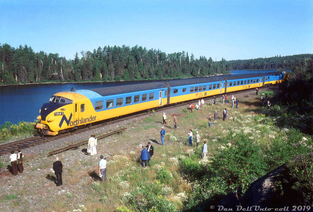 In August 1978, the Upper Canada Railway Society operated a four-day fantrip using one of Ontario Northland's recently acquired Northlander TEE trainsets. According to an old UCRS newsletter, the trip departed Toronto on Friday August the 4th and ran to North Bay. On the 5th it proceeded from North Bay to Timmins, on the 6th Timmins to Mosonee & back, and on Monday the 7th the train returned from Timmins back to Toronto. Here on the morning of the second day, fantrip attendees are stretching their legs and manning their cameras during a 9:15am runby stop at the remote location of Redwater, where the line runs alongside the Upper Redwater Lake.

Redwater, located at Mile 55.8 of ONR's Temagami Subdivision (about 16 miles south of Temagami), came into being in the early 1900's as a tiny settlement along the railway with a lumber mill, but research suggests it it became a deserted ghost town in the 1950's (note: calling it a "town" is a misnomer). After that, a few cottages sprung up at Redwater over time, and it was still noted in timetables as a stop for the ONR's Northlander passenger train, but its demise a few years back means the only access here today is via backroads.

Reuben S. Brouse photo, Dan Dell'Unto collection slide.