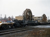 This picture shows the largest-diameter non-divisible internal part of the "Excalibore" Tunnel Boring Machine (TBM) riding in a special well car CN 670002. The TBM cutter, separated into 2 pieces, is on the flat car ahead. <br>
"Excalibore" components are travelling on a dimensional train powered by SD40u CN 6002 on CN's Dundas Sub in London ON, en route to the Toronto area after completing the bore of CN's new Sarnia Tunnel under the St.Clair River. <br>
I don't have the date of this movement, my guess is mid to late December 1994. Location is approximate.
