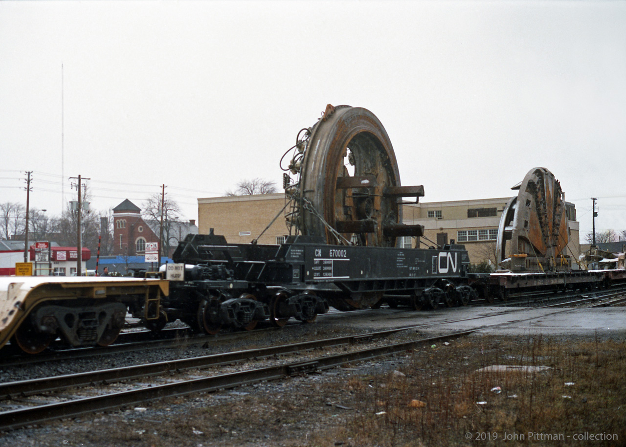 This picture shows the largest-diameter non-divisible internal part of the "Excalibore" Tunnel Boring Machine (TBM) riding in a special well car CN 670002. The TBM cutter, separated into 2 pieces, is on the flat car ahead. 
"Excalibore" components are travelling on a dimensional train powered by SD40u CN 6002 on CN's Dundas Sub in London ON, en route to the Toronto area after completing the bore of CN's new Sarnia Tunnel under the St.Clair River. 
I don't have the date of this movement, my guess is mid to late December 1994. Location is approximate.