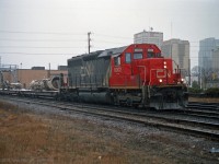 Construction of CN's new St Clair tunnel was preceded by a ceremony featuring the new white-painted Tunnel Boring Machine (TBM) "Excalibore" at the Sarnia portal of the tunnel on 16 September 1993.  <br>
The TBM broke through in Port Huron MI on 8 December 1994, about 8 months behind schedule. Much work remained; the first train though the new tunnel was on 5 April 1995.  <br><br>
Shortly after the break-through, the TBM was removed, dissassembled, loaded onto railcars and returned to Sarnia on the car ferry, en route back to the Toronto area. <br>
In this picture, components of the TBM are eastbound on the Dundas Sub near Colborne St in London Ontario, on a dimensional train powered by SD40u CN 6002.  Weather was marginal for photography and deteriorating. There isn't much paint left on Excalibore; it emerged from the bore with shiny bare metal, but now rust is showing.  <br>
I don't have the date of this movement, my guess is mid to late December 1994. Other frames from the film show the photographer met up with the train again in Stratford - unfortunately he experienced heavy rain/snow there. <br><br>
From other pictures I have been able to make out the train's 6 freight and 2 passenger cars: <br>
CN 667005  Flatcar - central auger of the TBM<br>
CN 667086  Flatcar - TBM part (spoil conveyor?)<br>
CN 667413  Flatcar - TBM front cutter, disassembled into 2 pieces<br>
CN 670002  4-truck special "well" car - Large diameter internal TBM part<br>
QTTX 30578 Depress Centre Flatcar -  half of the TBM outer body<br>
QTTX 30600 4-truck Depress Centre Flatcar - other half of TBM outer body<br>
CN 54954   6-axle Sleeper<br>
CN 70742   "Spirit of the North"  converted ex-Baggage car, few windows

