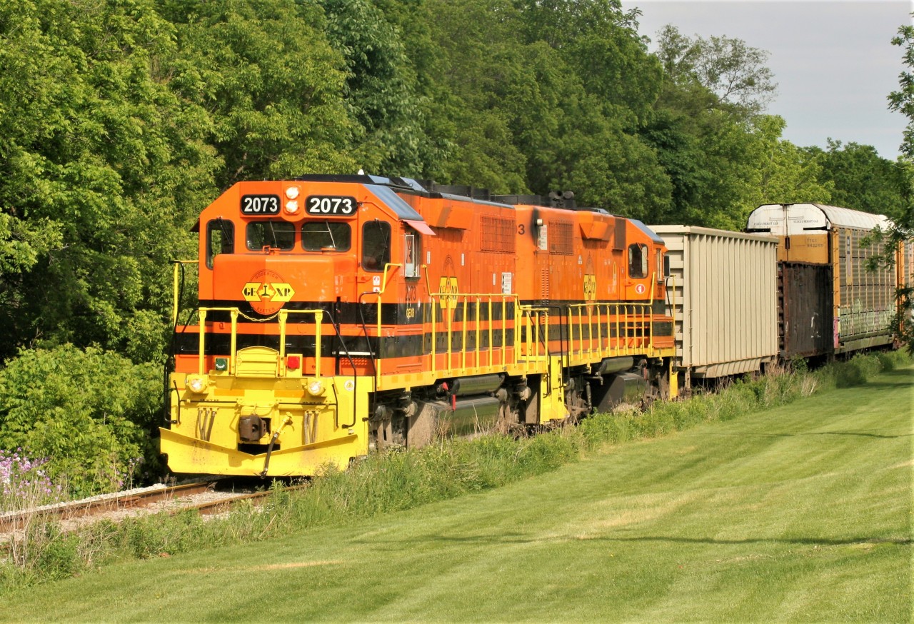 Goderich-Exeter Railway (GEXR) train 580 with GEXR GP38-3 2073 and GEXR GP39-2u 2303 is seen approaching Queen Street in Kitchener on the Huron Park Spur on June 6, 2018. The train is returning to the Kitchener yard with several cars lifted from the interchange with Canadian Pacific.