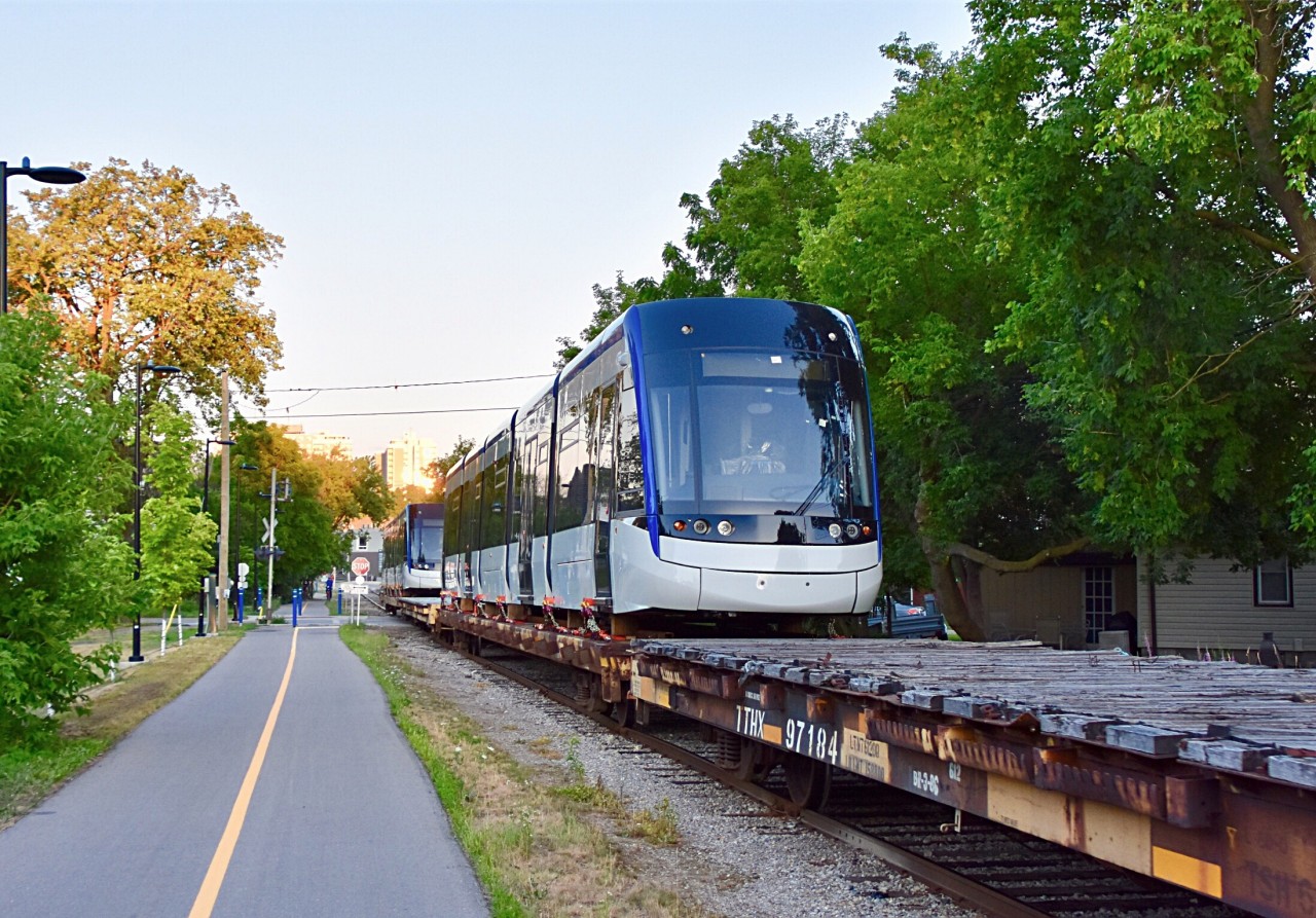 With Waterloo Regions LRT system said to be opening in less than a day now, I thought it would be a good time to share one of my favorite shots from last summer and it was of GEXR’s Kitchener-Elmira switcher (584) taking 2 of the brand new LRV Light Rail Vehicles up the Waterloo Spur with them on flatbeds (behind their usual short stash of tank cars) for delivery to the region! 
In this scene here the sun has just gone down and GEXR 584 has just began it’s 11 mile trip up the Waterloo Spur with the 2 of the brand new Light Rail Vehicles behind its 6 loaded tank cars. Right near the halfway point between Kitchener and Elmira, GEXR will set off the 2 new LRVs in the very rarely used spur to Commonwealth Plywood which is just about a mile north from the new ION Maintenance facility and from there the region will pick them up, unload them and get them ready for testing!! Time was 20:45 and photo was taken just north of the Wellington st crossing in Downtown Kitchener. GEXR power (out of sight) was 2303 and 2073.