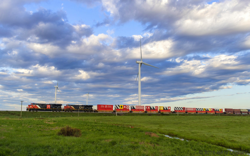 CN eastbound stack train Q120 heads by the turbines at Fort Lawrence, Nova Scotia, with the celebration CN 100 containers near the head end. They are destined for the next show at Halifax, Nova Scotia for next weekend. CN 3191 is also on the head end, sporting the CN 100 scheme. A nice touch.
