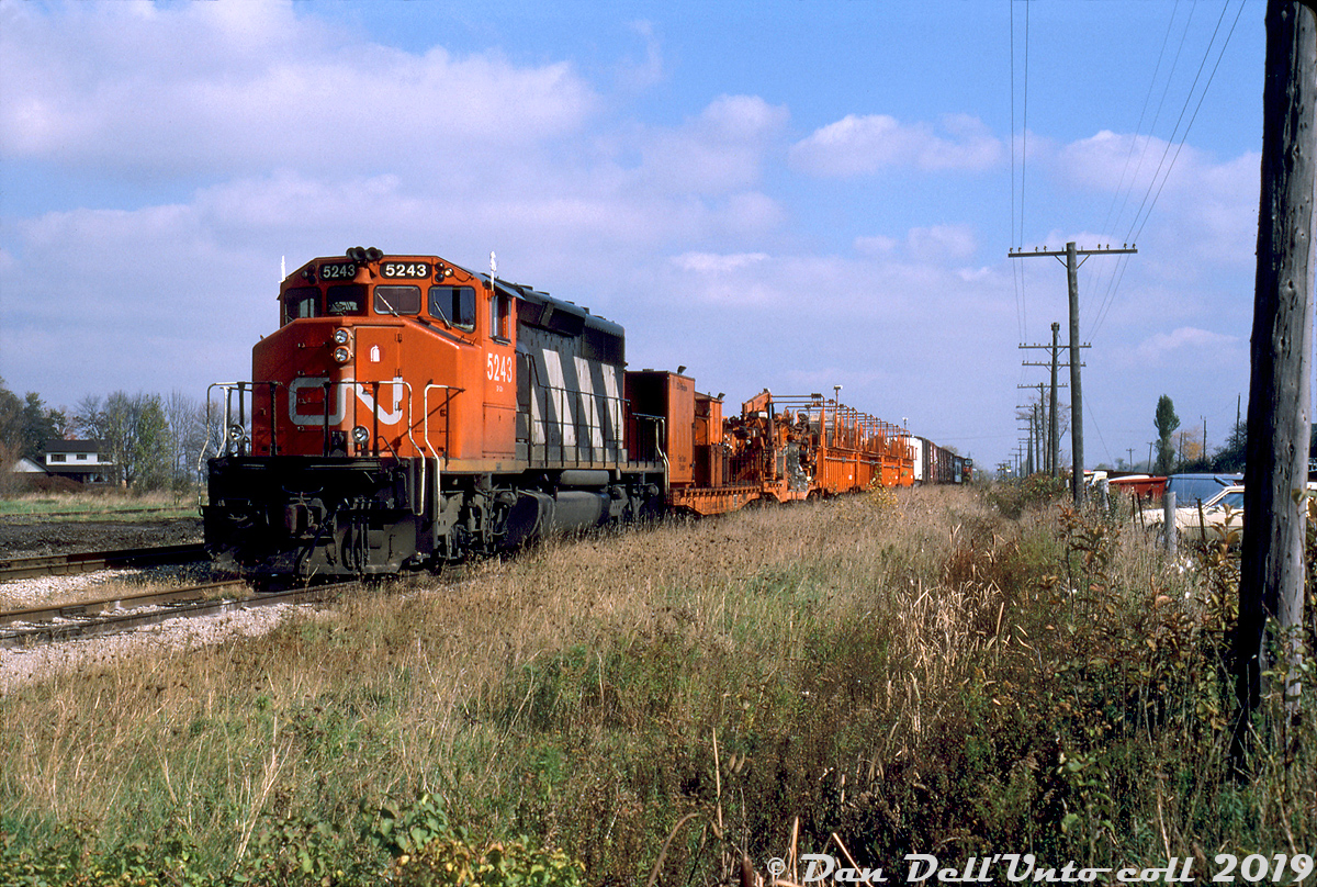 CN SD40-2W 5243 is the unit in charge of CN's Fibreplow train today, sitting at St. Mary's Junction awaiting their next call to duty.

The Fibreplow (or Fibre Plow) was used by CN's Signals & Communications department to install fibre optic cable along CN's mainlines all across southern Ontario, starting in the mid-80's. Power was usually one SD40-2W, pulling a pair of specially modified flatcars (one equipped with trenching/ditching equipment, including the "plows" that cut deep trenches alongside the track and fed fibre optic cable down), and a few specially-modified gondolas equipped with racks that carried fibre optic cable reels that were fed to the plow. An assortment of work cars usually followed. At the time, they were plowing and laying fibre optic in the St. Marys and London areas. Photos from 1986 show trackage around Guelph, Burlington, the Halton Sub, the Weston Sub, St. Marys and London was all done.

For the modellers out there, two of the orange gondolas used on the Fibre Plow were done as part of one of Rapido Train's Canadian gondola releases, sans racks of course (I wonder who it was that tipped them off about those cars...hmmm!)

Gord Taylor photo, Dan Dell'Unto collection.