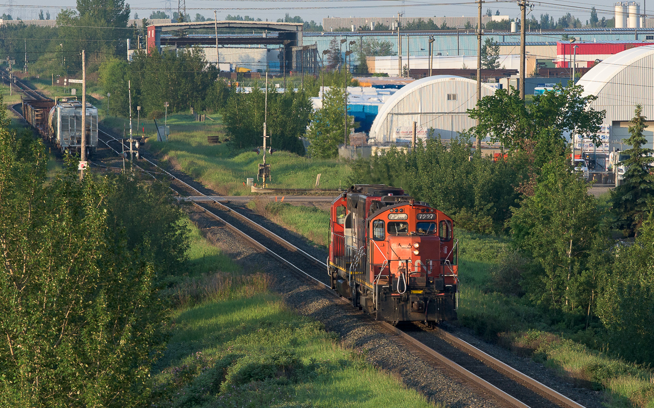 Going over the tracks on the Sherwood Park Fwy., I catch a glimpse of the 7227 sitting down below. They are asking for permission to go through the work area set up for replacing the East Edmonton diamond. In the distance down the tracks you can see the CN Strathcona sign and siding. The track curving off to the right from the mainline (you can see the red target on the switch) is the Strathcona spur. Although still of some length (over 6km's now compared to over 9km's in the past) it serves only a few customers. That is the WC 3027 tucked in behind.